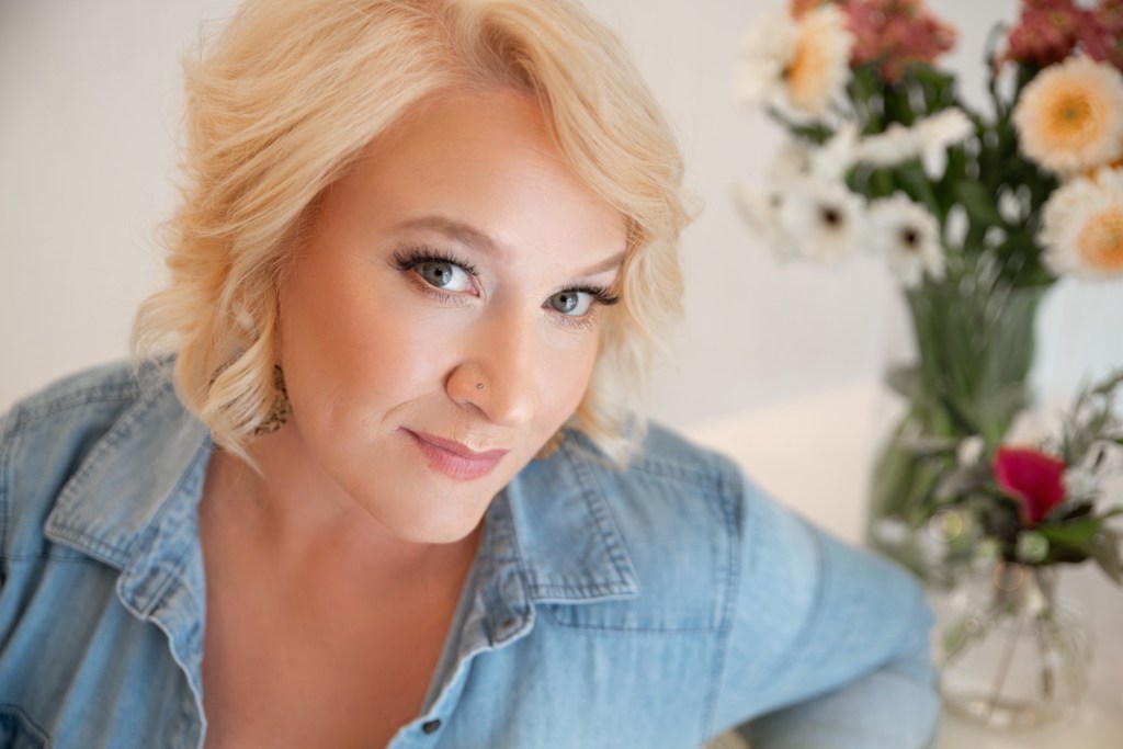 Katie Kerr, owner of Bloom & Forage, sits at a desk in a relaxed workspace, reflecting a calm and intentional approach to wedding planning, coordination, and floral design.